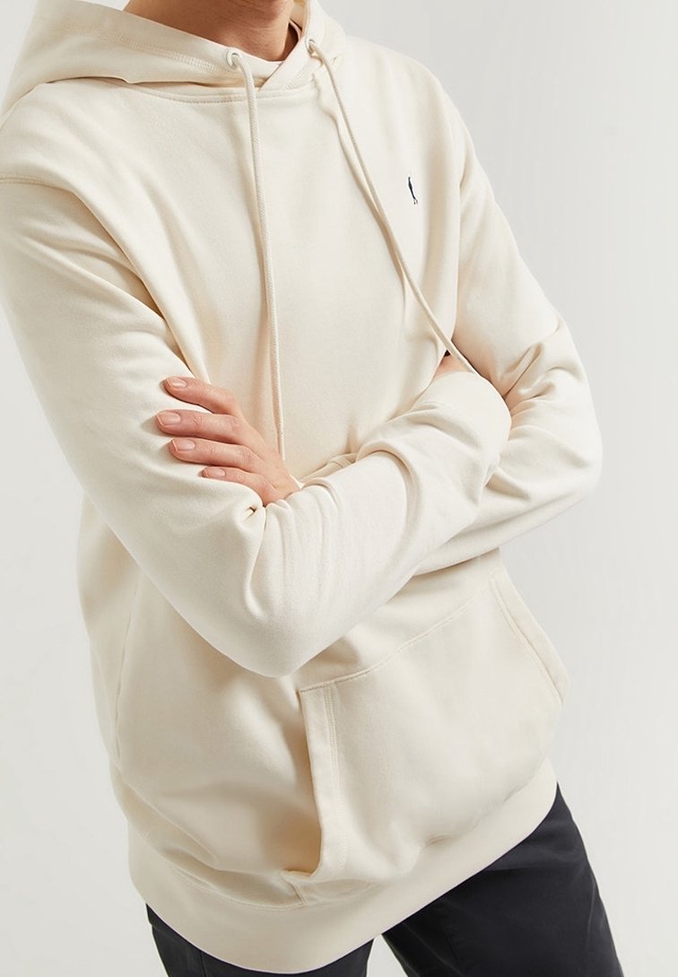 Krémová mikina s kapucí z měkké látky s přední kapsou kangaroo a šňůrkami. Na hrudi je decentní logo. Klasický střih s dlouhými rukávy.