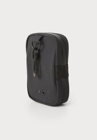 Schwarze Stofftasche mit Reißverschluss und einem Clip. Verfügt über eine strukturierte Oberfläche und zwei Belüftungsöffnungen an der Unterseite. Kompaktes Design.