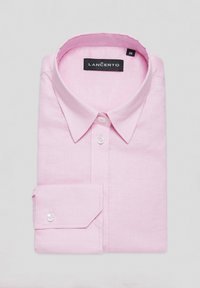 Jasnoróżowa koszula z długim rękawem, wykonana z lnu. Posiada tradycyjny kołnierzyk, zapięcie na guziki z przodu oraz mankiet zapinany na jeden guzik. Widoczna metka marki.