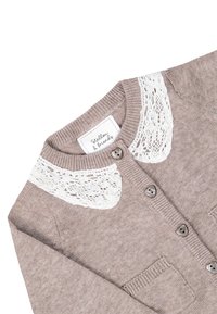 Cardigan lavorato a maglia marrone chiaro con colletto in pizzo bianco, dotato di bottoni grigi e due tasche frontali. Texture morbida e design classico.