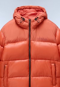 Jasně oranžová prošívaná bunda s kapucí, s předním zipem a bočními kapsami. Hladká, prošívaná textura s lehkým vzhledem.
