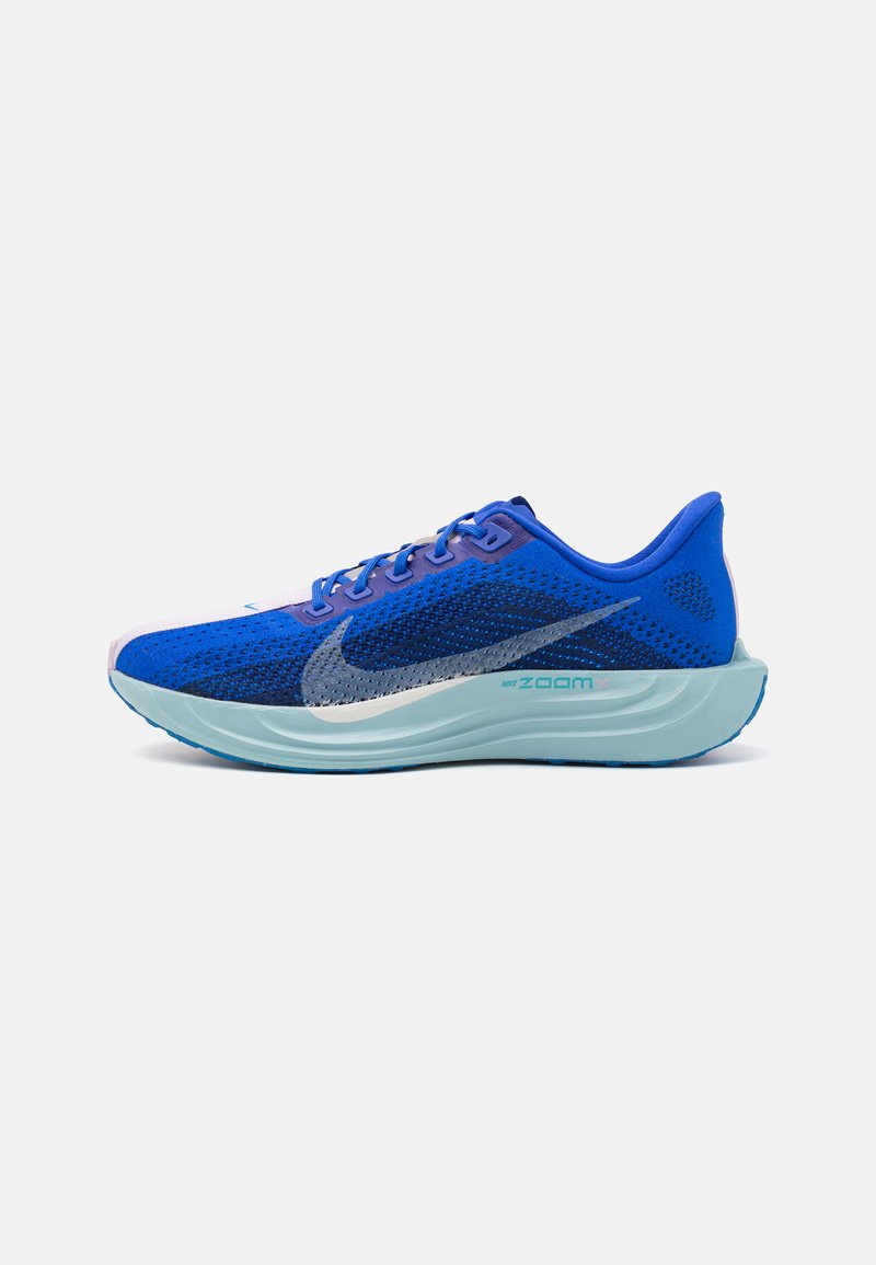 Zili sporta apavi ar sietu augšējo daļu, kontrastējošiem tumšākas zilas krāsas akcentiem, pelēku Nike simbolu un gaiši zilu gumijas zoli.
