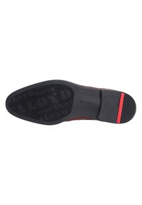 Suola di scarpa in pelle marrone con gomma nera testurizzata. Presenta un accento rosso sul tallone e il nome del marchio in rilievo. Design piatto.