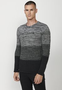 Pulover texturat în nuanțe de gri și negru, cu mâneci lungi, decolteu rotund și un detaliu mic cu logo pe piept. Materialul este un tricot neted.