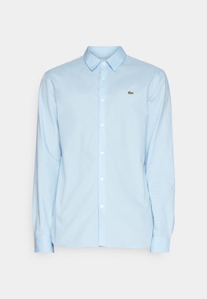 Light blue long-sleeve shirt made of smooth fabric, featuring a classic collar, button-down front, and a small green logo on the chest.