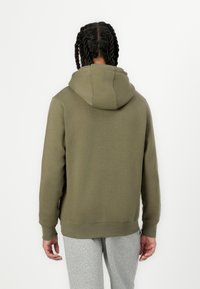 Φούτερ με κουκούλα σε ελιά πράσινο χρώμα, με λεία υφή, άνετη εφαρμογή και ριμπ μανσέτες. Διαθέτει τσέπη καγκουρό και ενισχυμένες ραφές.