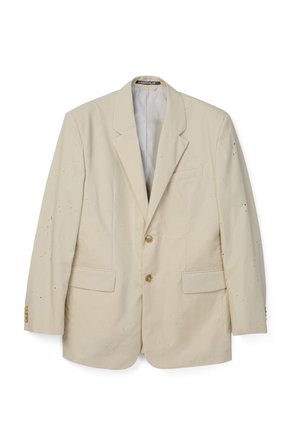 Beige single-breasted blazer with two buttons, notch lapels, flap pockets, and small scattered holes throughout the fabric.