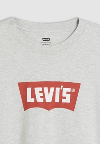 T-shirt de algodão cinza com um grande logotipo vermelho da Levi's com texto branco. Design de gola redonda com um ajuste vintage e textura suave.