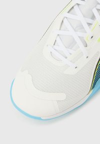 Άσπρο αθλητικό παπούτσι με επ άνω μέρος από υφασμάτινο δίχτυ με υφή, άσπρα κορδόνια και απαλές νέον κίτρινες λεπτομέρειες, με σόλα από ελαστικό σε ανοιχτό μπλε χρώμα.