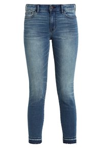 Jeans de denim azul con un ajuste slim, que presentan secciones desgastadas, cinco bolsillos y un dobladillo deshilachado. La tela tiene una textura suave.