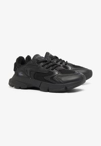 Zapatillas deportivas negras con parte superior de malla y superposiciones sintéticas. Presentan una suela texturizada, collar acolchado y cordones negros. Logo de la marca visible.