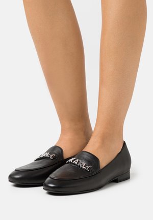 Black leather loafers with a smooth texture, slip-on design, and silver hardware detailing on the front featuring the name "KARL."