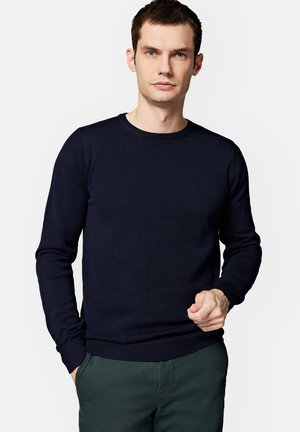Granatowy sweter wykonany na drutach z okrągłym dekoltem, z prążkowanymi mankietami i dołem. Minimalistyczny design z małym logo na klatce piersiowej.