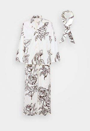 Hvid pyjamas sæt med brun blomsterprint. Funktionen inkluderer en skjortepolo og brede bukser. Sammen med et matchende mønster tørklæde.