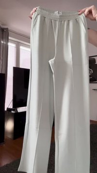 Pantalones de color verde claro con una cinturilla elástica, piernas rectas y dos bolsillos laterales. La tela tiene una textura suave y pocas arrugas.
