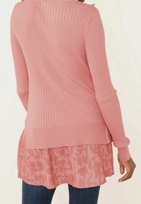 Roze geribbelde lange mouwen sweater, gelaagd over een doorschijnend roze gepatterd top, met een ronde zoom en fitted manchetten.
