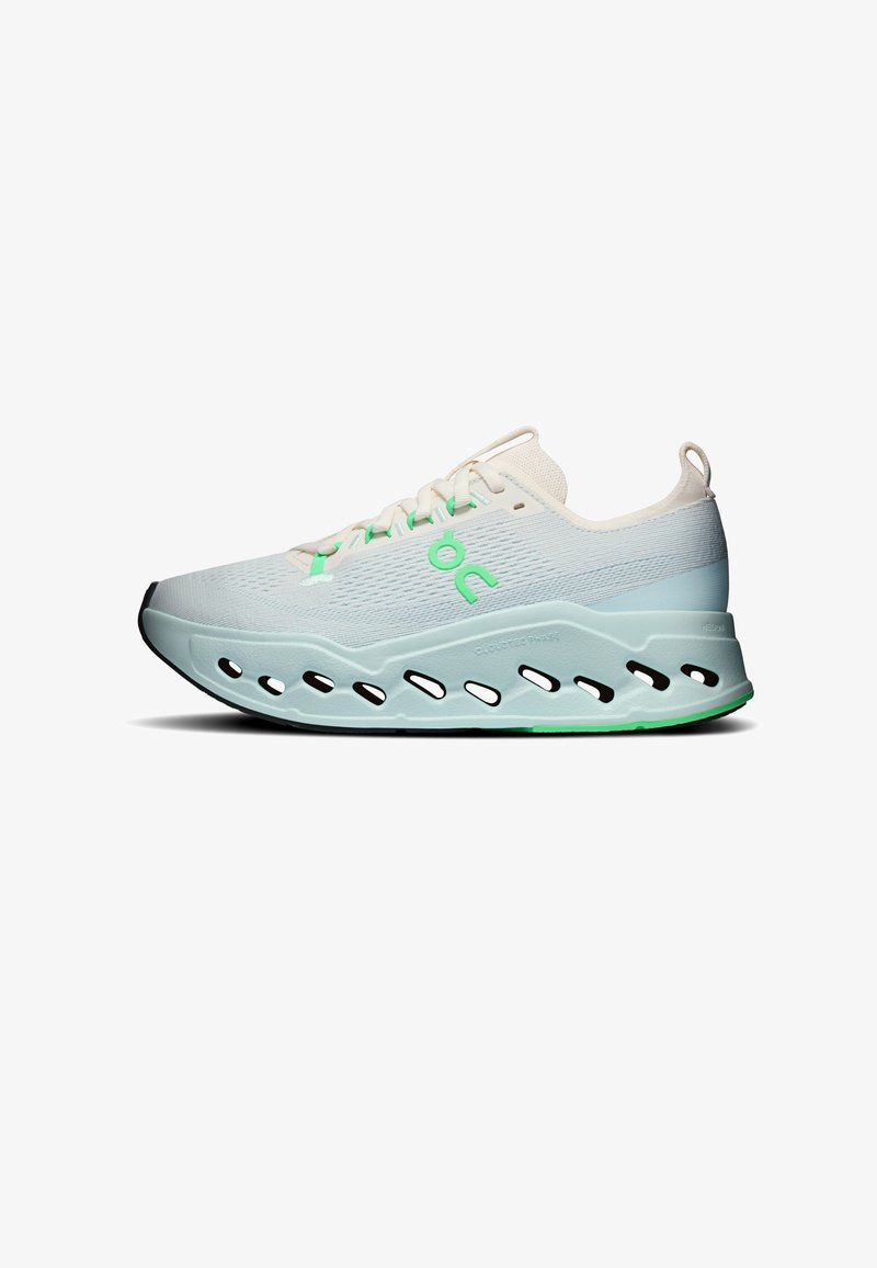 Chaussure de course blanche et bleu clair avec des accents verts, semelle épaisse avec découpes ovales et une boucle au talon, vue de côté.