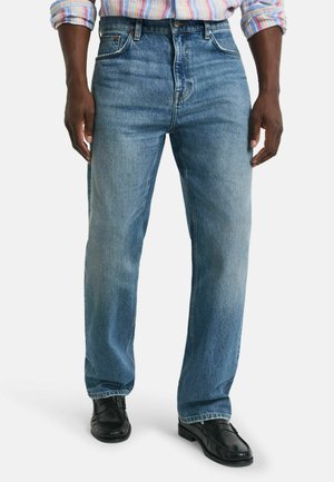 Jeans in denim blu chiaro con un design a gamba dritta, cinque tasche e una sottile texture sbiadita. Indossati con scarpe in pelle nere.