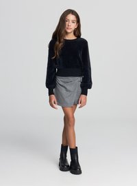 Czarny, puchaty, krótki sweter z długimi rękawami, zestawiony z szarą, prążkowaną spódnicą kopertową i czarnymi botkami za kostkę. Gładkie tekstury i warstwowy wygląd.