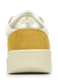 Sneaker bianca con tallone in suede giallo, dettagli metallici oro e suola in gomma crema testurizzata. Presenta il marchio "Gola" sul tallone.