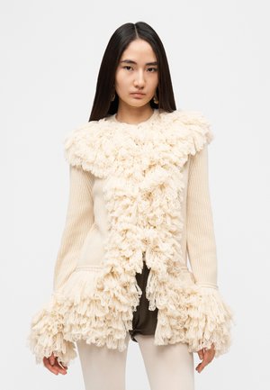 Pull de couleur crème avec franges texturées le long du col et des manches ; design côtelé ; devant ouvert ; manches longues ; texture de tissu douce.