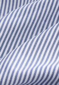 Bomuldsstof med skiftevis blå og hvide striber. Teksturen er glat med et vævet udseende. Linjerne er jævnt fordelt.