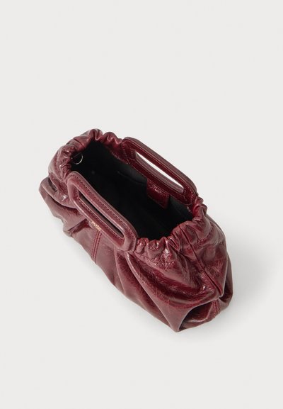 Petit sac pochette en cuir bordeaux avec bords supérieurs froncés et anses rectangulaires ajourées, montré ouvert vu de dessus sur fond blanc.