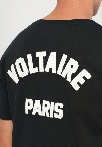 Svart bomull T-skjorte med hvit brodert tekst "VOLTAIRE" buet over "PARIS" på baksiden. Klassisk crew neck-design.
