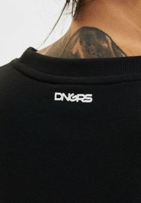 Čierna mikina s pružným výstrihom a bielym vyšitým logom "DNGRS" na zadnej strane, s hladkou textilnou štruktúrou.