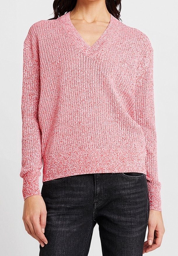 Maglione rosa a maglia con scollo a V, maniche lunghe e vestibilità rilassata. Presenta un motivo testurizzato e polsini a coste, abbinato a jeans scuri.