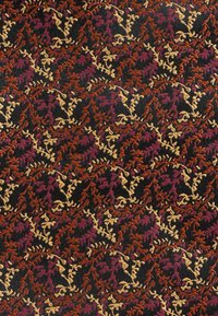 Tät vävd tyg med intrikata blad- och vinmönster i rost, senap och vinrött på en svart bakgrund.