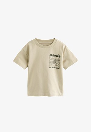 Beżowy t-shirt z krótkim rękawem z czarną grafiką przedstawiającą scenę uliczną, napis "oasis" nad i "BE HERE NOW" pod ilustracją na piersi.
