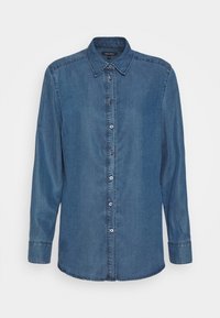 Blå denimskjorta med knappstängning, långa ärmar och klassisk krage. Har synliga sömmar och matchande knappar.