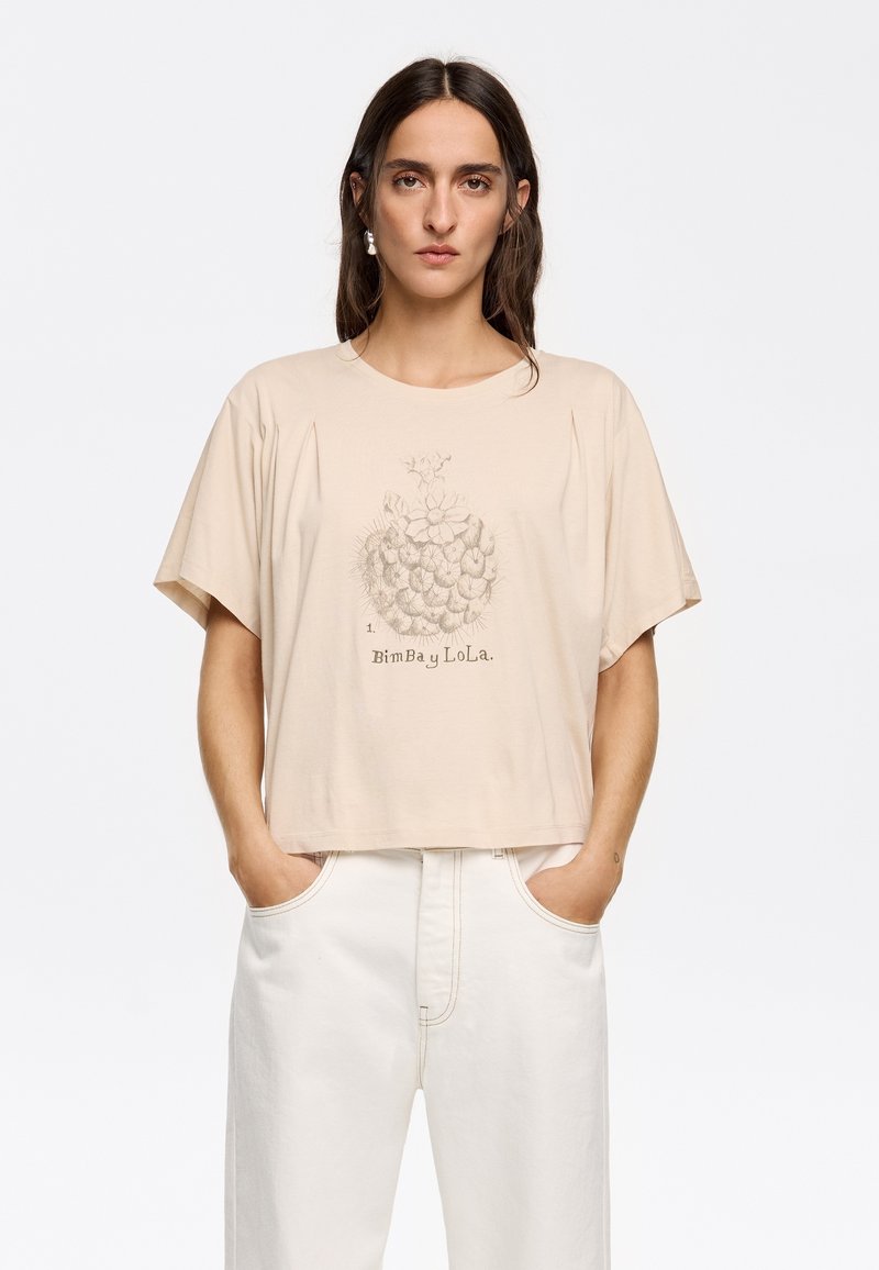 T-shirt beige a maniche corte con una vestibilità ampia, caratterizzata da una grafica testurizzata di un cactus e il nome del marchio "Bimba y Lola" stampato sotto.