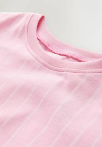 Różowa bawełniana koszulka z okrągłym dekoltem i subtelnymi pionowymi paskami. Miękka struktura z elastycznym krojem i starannie wykończonymi szwami.