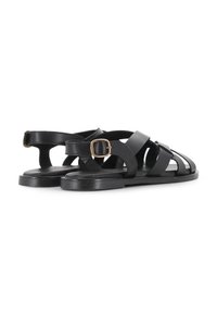 Sandalias de cuero negro con tiras entrelazadas, hebilla ajustable en el tobillo, suela plana y textura suave. Diseño minimalista.