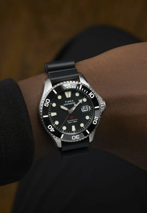 Timex Deepwater Uhr mit schwarzem Zifferblatt, Edelstahlgehäuse und Silikonarmband; verfügt über große leuchtende Stundenmarker und ein Datumsfenster.