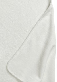 Valkoinen froteekangas, jossa on pehmeä, teksturoitu pinta ja sileät, pyöristetyt reunat. Siinä on hieman kiiltoa ja siistit tikkaukset reunojen ympäri.