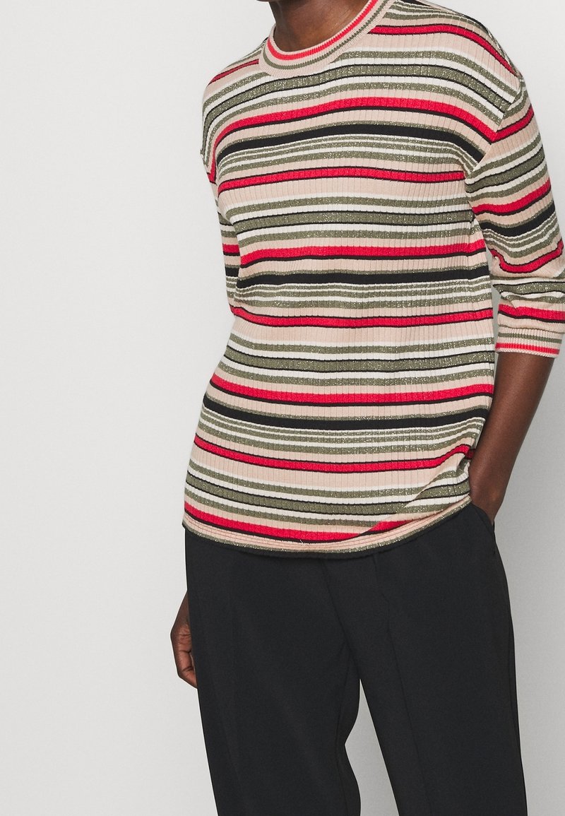Top de punto a rayas con líneas horizontales en rojo, verde, beige y negro con acentos metálicos; cuello redondo; mangas de tres cuartos.