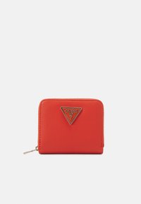 Portefeuille en cuir rouge texturé avec un logo triangulaire doré. Il présente une fermeture éclair et une forme rectangulaire compacte.
