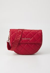 Röd kviltad lädercrossbody-väska med guldlogo, en böjd form och justerbar rem med varumärkesnamnet i röd färg.