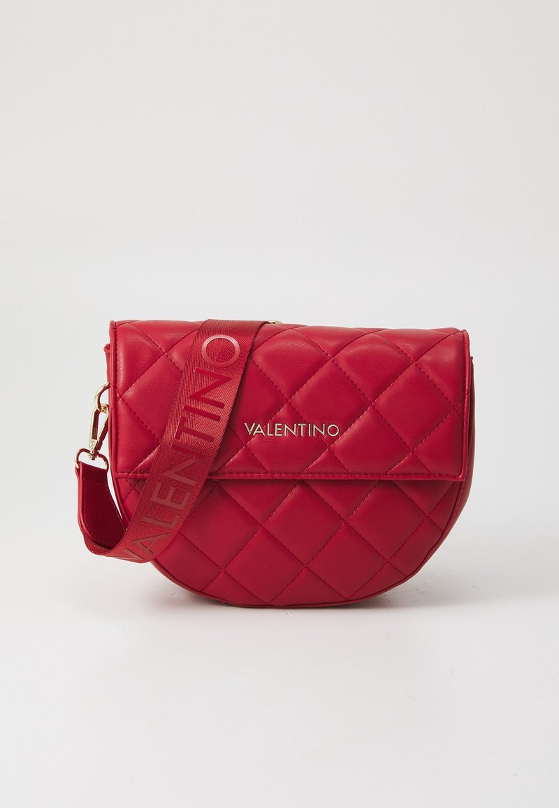 Röd kviltad lädercrossbody-väska med guldlogo, en böjd form och justerbar rem med varumärkesnamnet i röd färg.