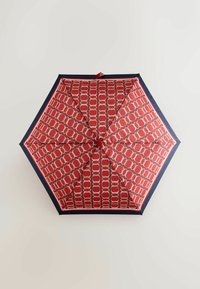Rød paraply med et geometrisk mønster i creme, med en marineblå kant. Sekskantet form, blankt stof og en central knap.