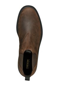 Stivale da caviglia in pelle marrone con pannelli elastici laterali, punta rotonda e suola in gomma nera a contrasto. Presenta il logo dorato all'interno.