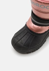 Schwarzer Gummischneestiefel mit einem pinkfarbenen, metallischen Schaft, der eine abgerundete Spitze, vertikale Rillen und einen schwarzen elastischen Riemen mit reflektierenden Akzenten aufweist.