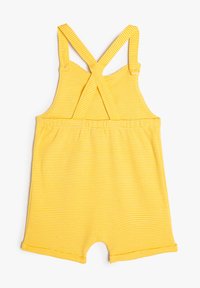 Mono amarillo a rayas con tirantes cruzados, cintura elástica y diseño de pierna abierta. Textura de tela suave, estilo casual para clima cálido.