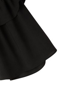Tessuto nero con una superficie morbida e leggermente strutturata, caratterizzato da un design stratificato con un orlo arrotondato e cuciture visibili lungo i bordi.
