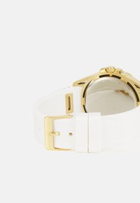 Cinturino per orologio in silicone bianco con fibbia in metallo dorato e cassa dell'orologio color oro. Vetro trasparente con meccanismi dell'orologio visibili all'interno.