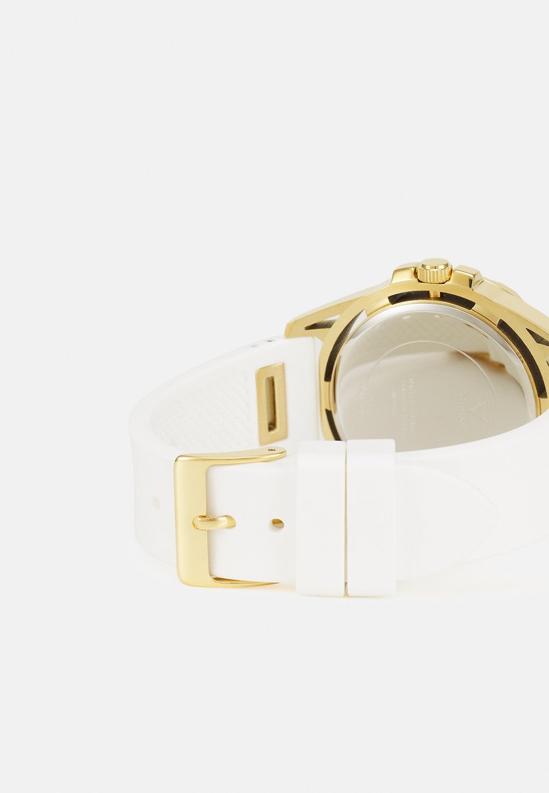 Cinturino per orologio in silicone bianco con fibbia in metallo dorato e cassa dell'orologio color oro. Vetro trasparente con meccanismi dell'orologio visibili all'interno.