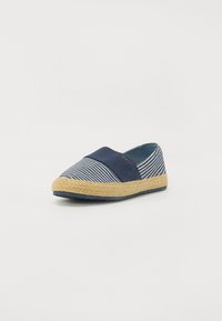 Espadrille rayé bleu marine et blanc avec une semelle en corde de jute et un dessus en toile bleu marine uni, doté d'un bandeau élastique pour un ajustement parfait.